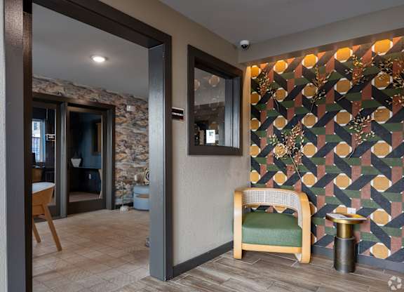 A room with a chair and a table in front of a patterned wall.