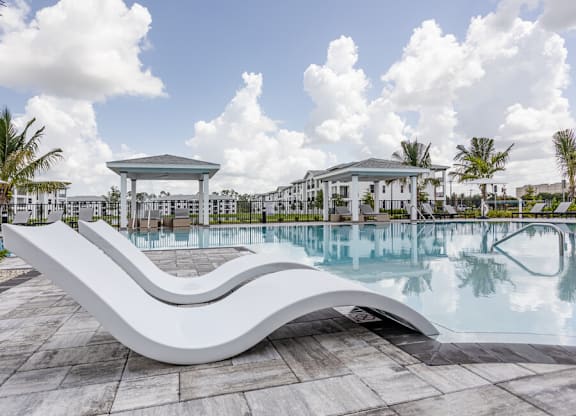 A white, curved bench sits in front of a pool.