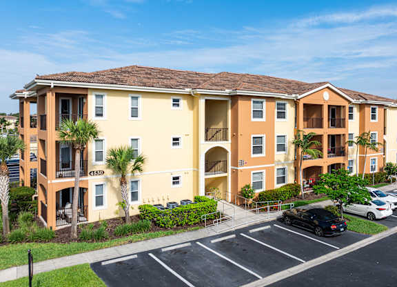 A large apartment complex with a parking lot in front.