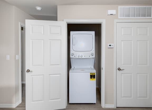 A white fridge is in a room with two white doors.