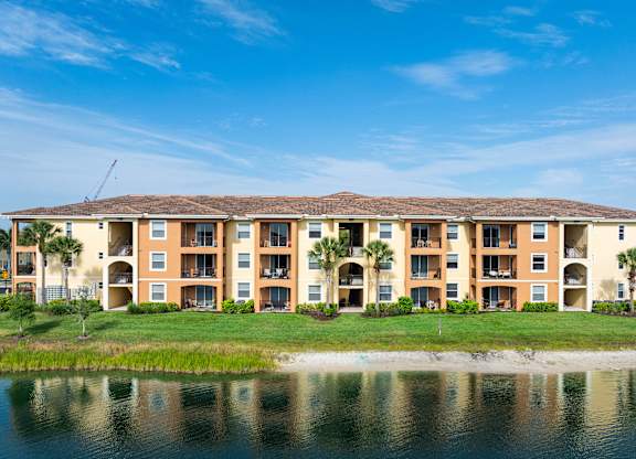 A large apartment complex with a body of water in front.
