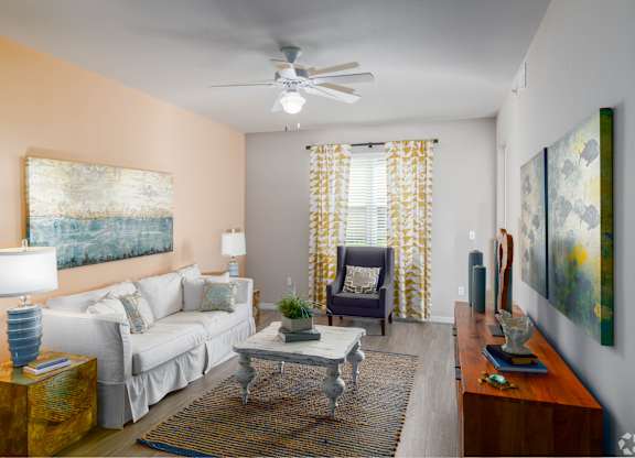 A living room with a white couch, a coffee table, and a painting on the wall.