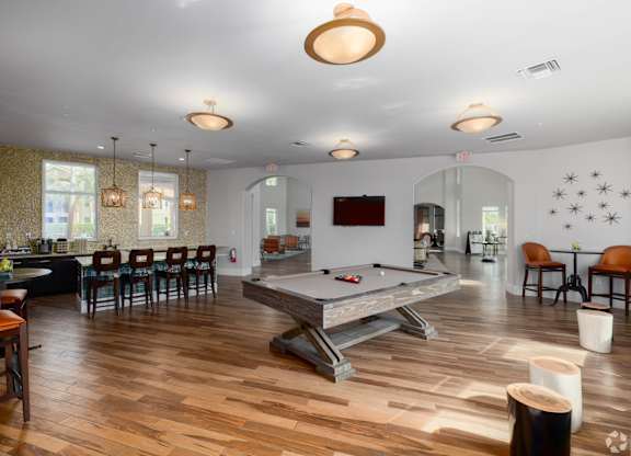 A pool table is in the middle of a room with a wood floor.