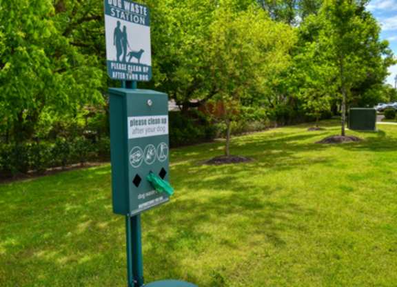 A sign in a park instructs people to clean up after their dogs.