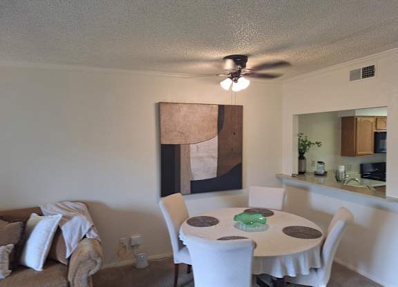 A living room with a brown couch and a painting on the wall.