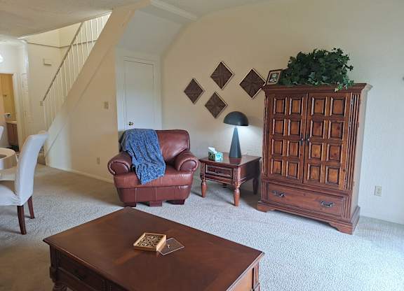 A living room with a brown leather couch, a wooden cabinet, and a coffee table.