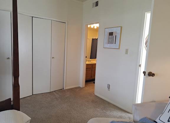 A bedroom with a white bed and a picture on the wall.
