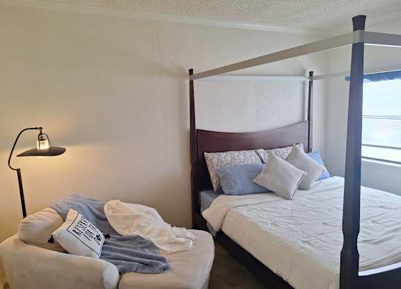 A bedroom with a bed and a lamp.