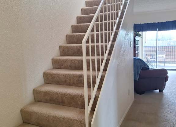 A staircase with beige carpeted steps and white railings.