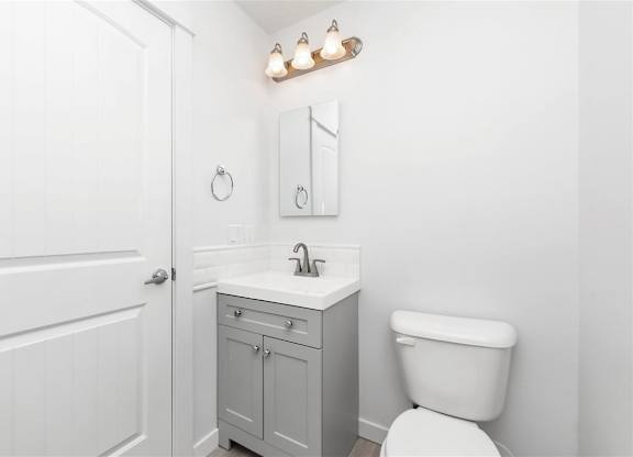 A white bathroom with a toilet, sink, and medicine cabinet.