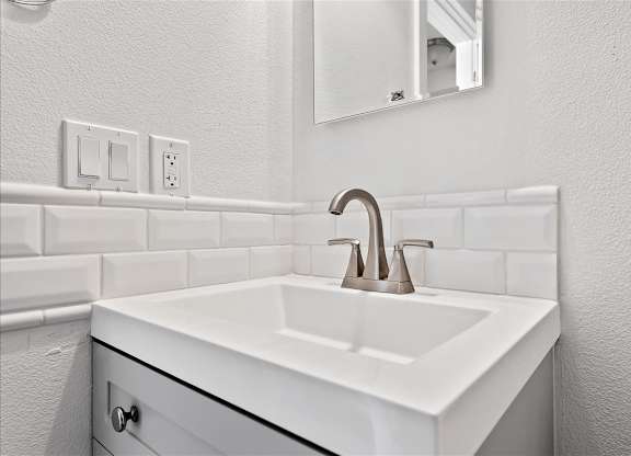 A white sink in a bathroom with a brown faucet.