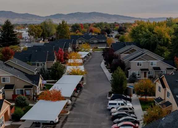 A residential street with houses on both sides and cars parked on the side of the road.