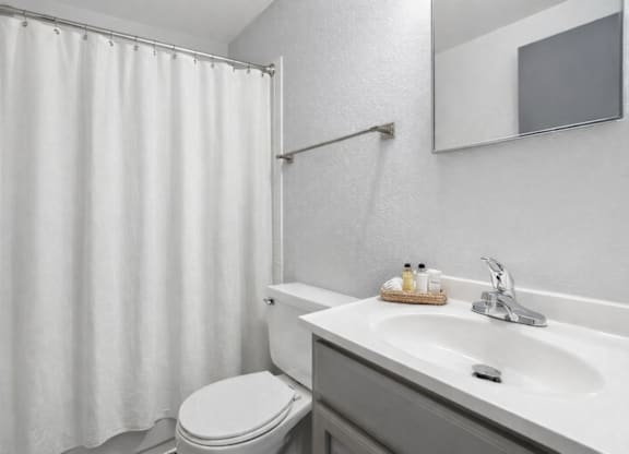 A white bathroom with a toilet, sink, and shower curtain.