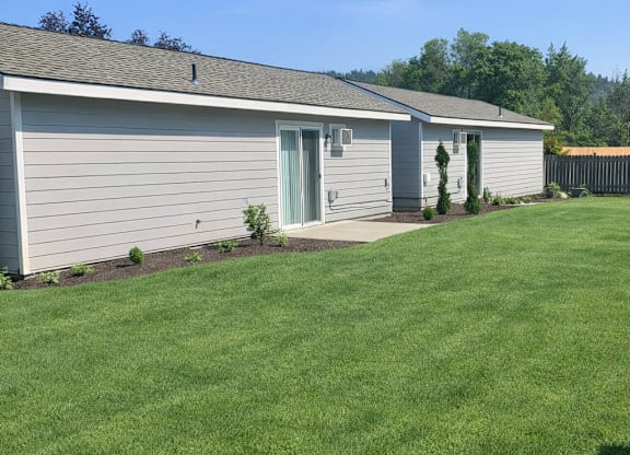 A house with a grey roof and a green lawn in front.