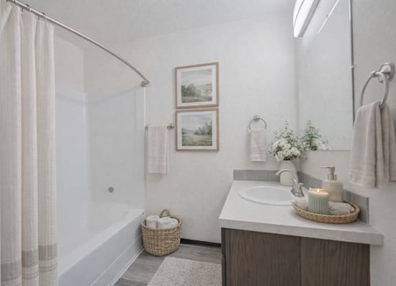 A bathroom with a white sink and a white shower curtain.