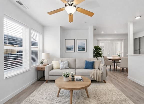 A living room with a couch, a coffee table, and a ceiling fan.