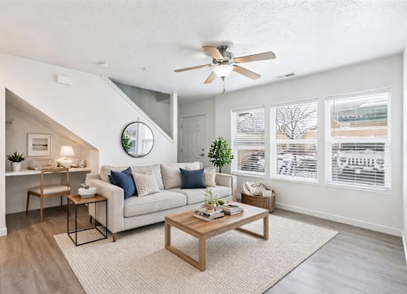A living room with a couch, a coffee table, and a ceiling fan.