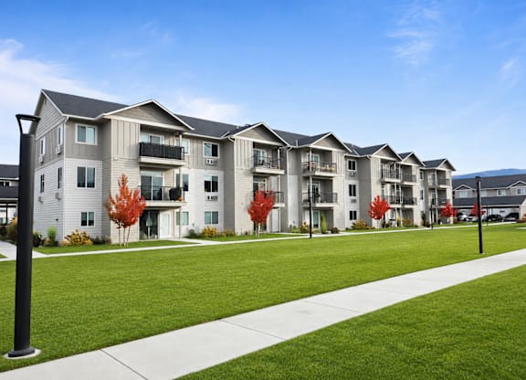 A row of modern apartment buildings with green lawns in front.