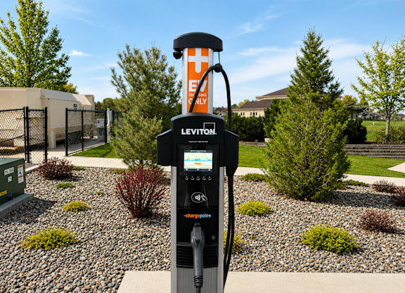 A Leviton electric vehicle charging station sits in a landscaped area.