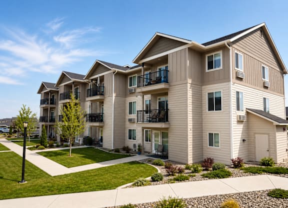 A large, modern apartment building with a well-maintained lawn in front.