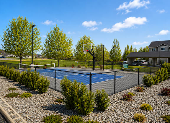 A basketball court is surrounded by a fence and has a blue surface.