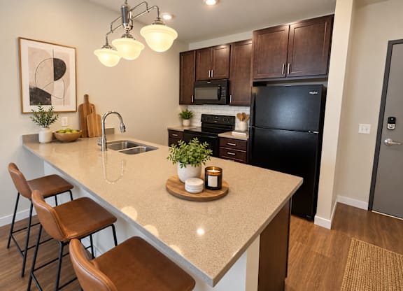 A kitchen with a black refrigerator and brown stools.