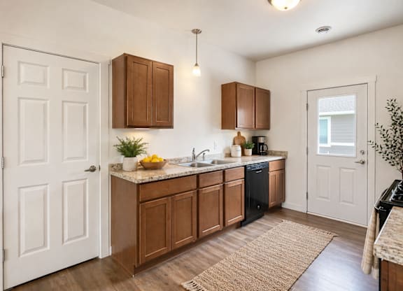 A kitchen with brown cabinets and a black dishwasher.