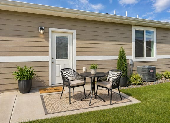 A patio with a table and chairs is set up outside a house.