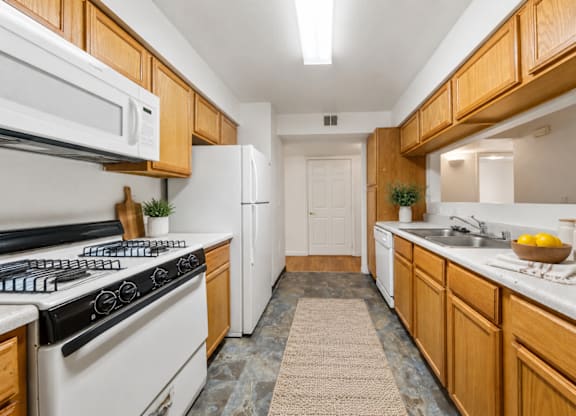 A kitchen with wooden cabinets and a white stove top oven.