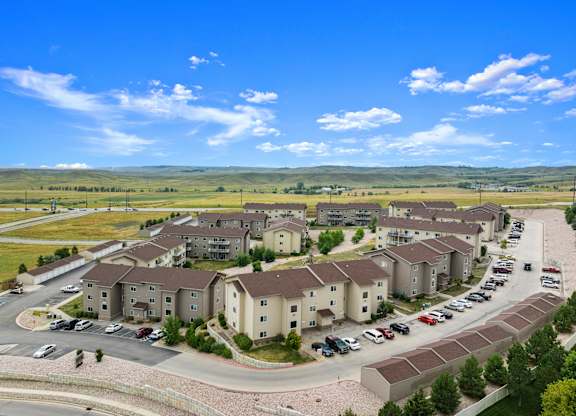 A large apartment complex with a parking lot in front.