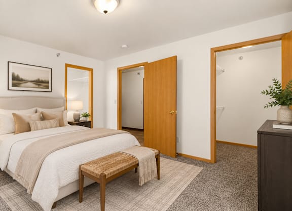 A bedroom with a bed, a bench, and a painting on the wall.