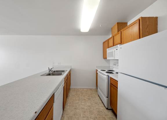 A kitchen with white appliances and wooden cabinets.