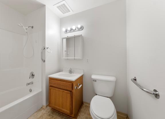 A white toilet sits next to a white sink in a small bathroom.