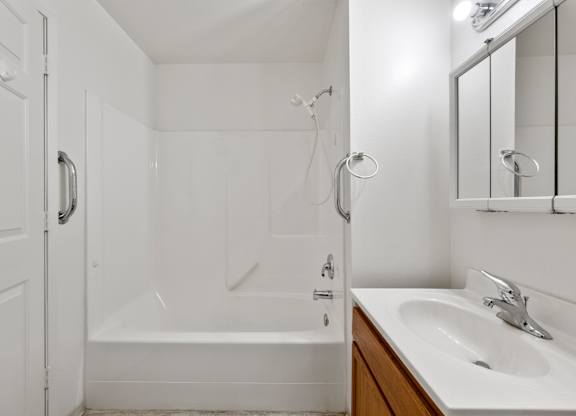 A white bathroom with a tub, sink, and mirror.