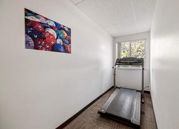 A treadmill is in a room with a painting on the wall.