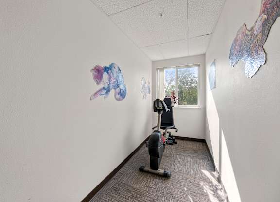 A person is working out on a stationary bike in a room with artwork on the wall.