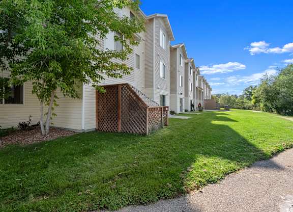 A row of houses with green lawns and trees in front.