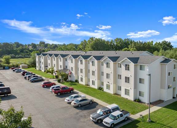 A parking lot in front of a white apartment building.