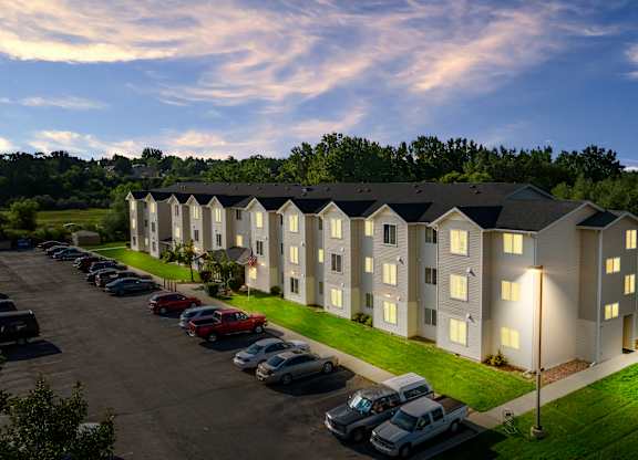 A parking lot with cars and a building with lights on.