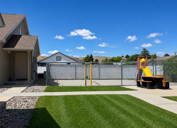 A playground with a slide and a fence in the background.