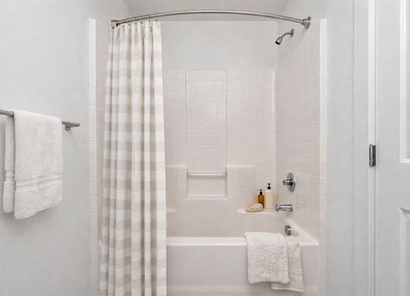 A white bathroom with a shower curtain and a white tub.