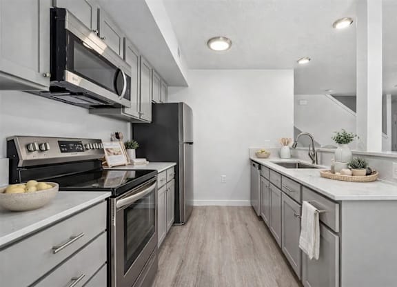 A modern kitchen with a black refrigerator and stove top oven.