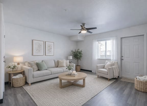 A living room with a white couch, a coffee table, and a ceiling fan.