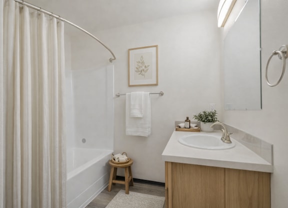 A bathroom with a white sink and a white shower curtain.