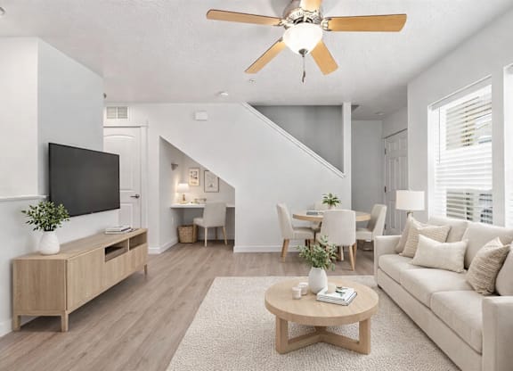 A living room with a white couch, a wooden coffee table, and a ceiling fan.