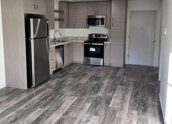 A kitchen with a refrigerator, microwave, oven, and sink.