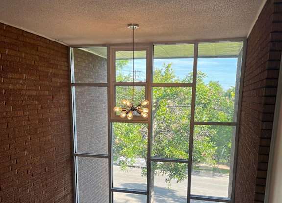 A view of a street through a window with a chandelier hanging from the ceiling.