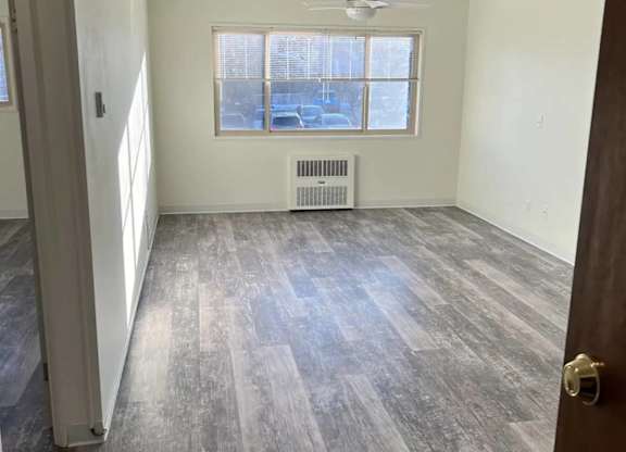 A room with a grey floor and a window with blinds.