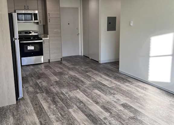 A modern kitchen with a wood floor and a ceiling fan.