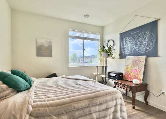 A bedroom with a large bed and a window overlooking the street.
